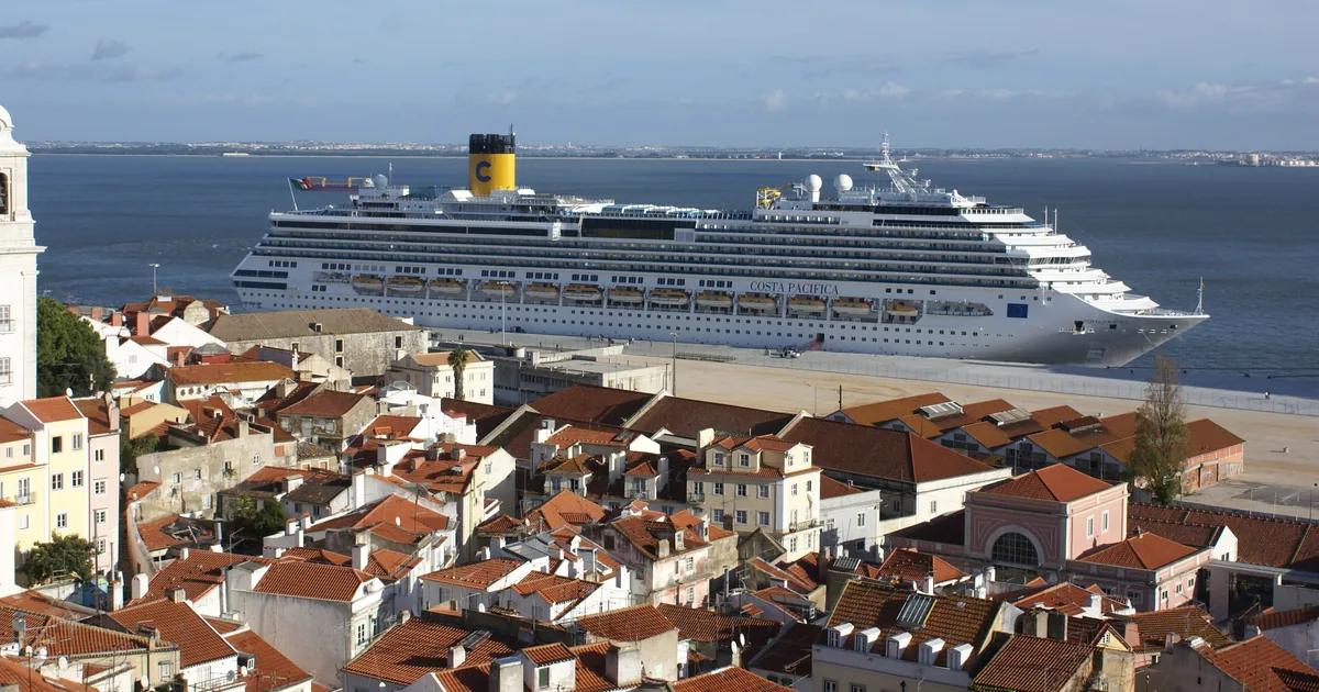 Tejados de la Alfama de Lisboa bajando hacia el Tajo, con un barco cruzando el río al fondo.